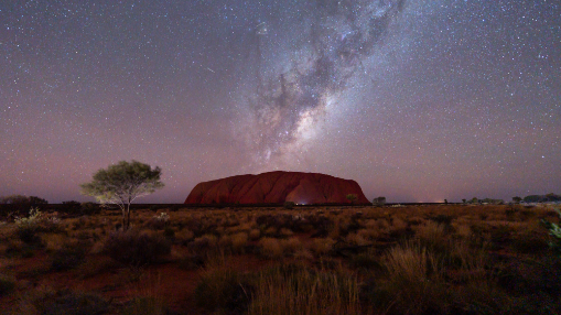 The Milky Way rises above the epic desert landscape of Uluru
