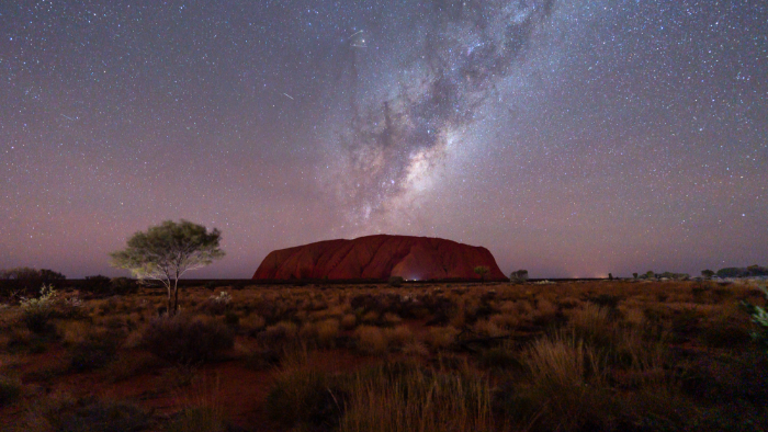 The Milky Way rises above the epic desert landscape of Uluru