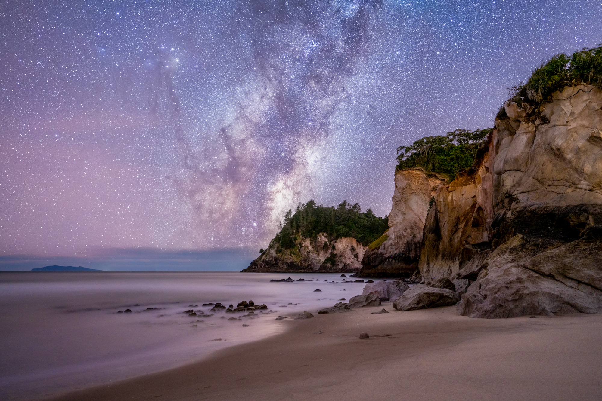 The Milky Way rises over cliffs on the Coromandel coastline in NZ. It looks serene but was VERY windy! 